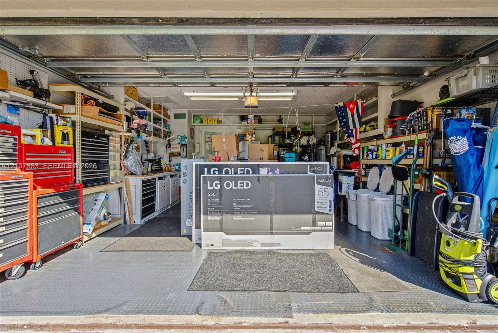 Garage space featuring built-in industrial shelving, integrated workbench cabinetry, textured floor matting, and overhead fluorescent lighting