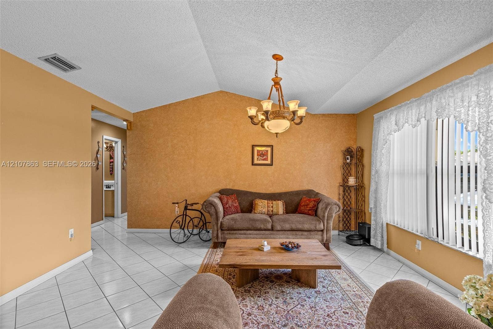 Vaulted ceilings featuring a central multi-arm chandelier and diagonal-set ceramic tile flooring