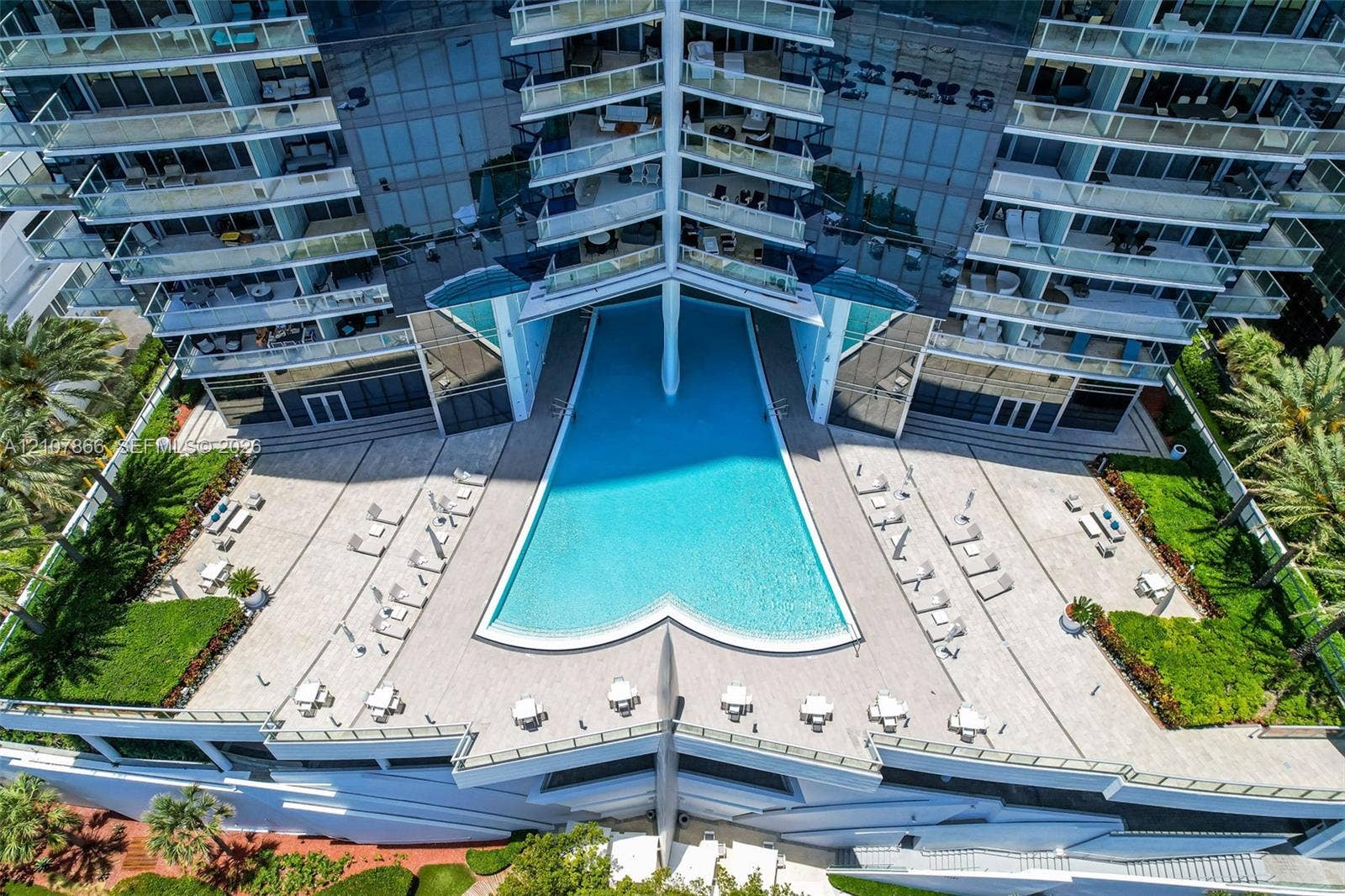 17121 Collins Avenue, #2608, Sunny Isles Beach, FL 33160 High-rise pool terrace featuring a geometric swimming pool, paved sundeck, glass-railed balconies, and landscaped grounds