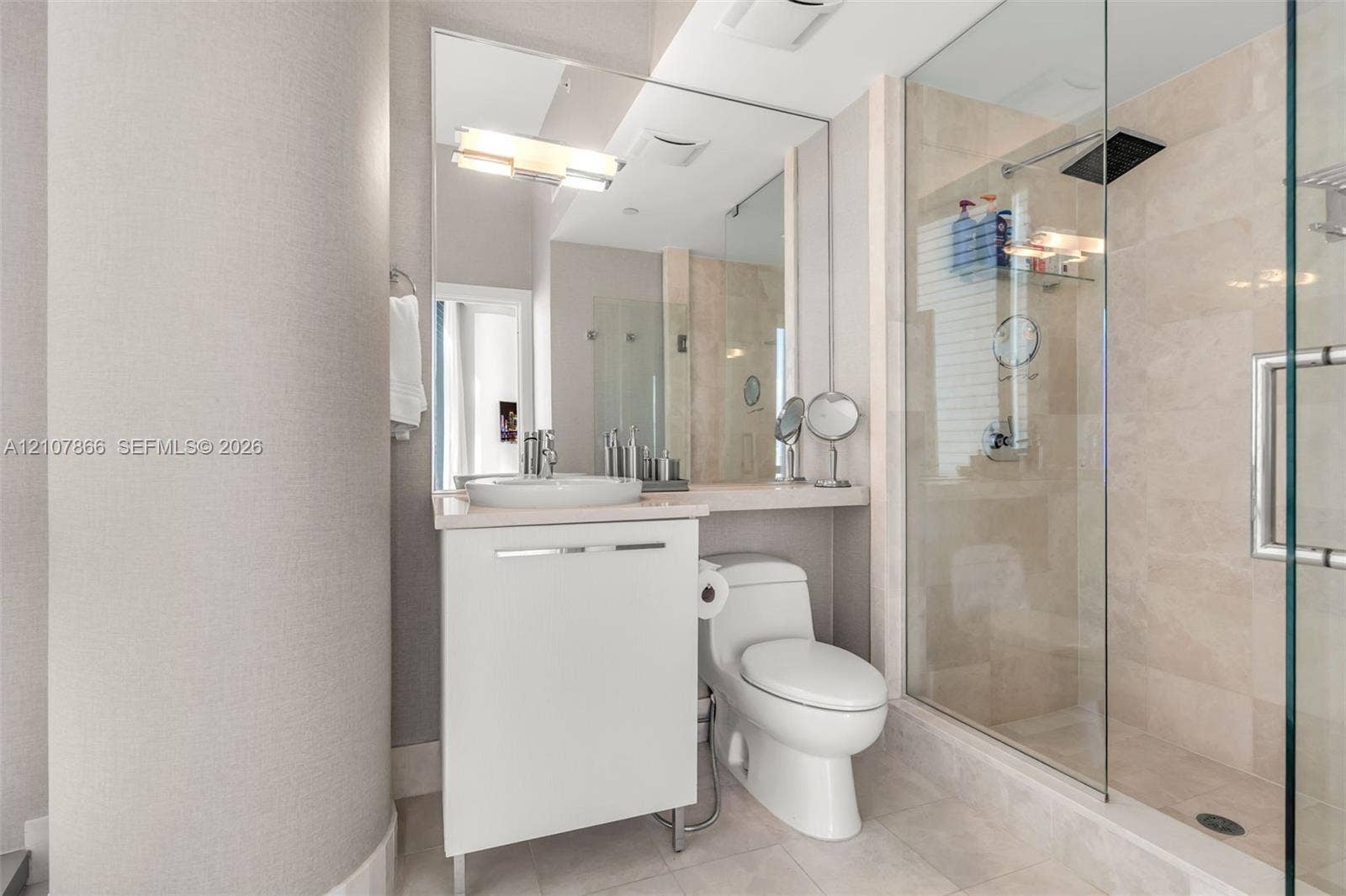 17121 Collins Avenue, #2608, Sunny Isles Beach, FL 33160 Bathroom featuring a white vanity with a vessel sink, a full-length wall mirror, a glass-enclosed walk-in shower with stone-tile surround, and a rain-style showerhead