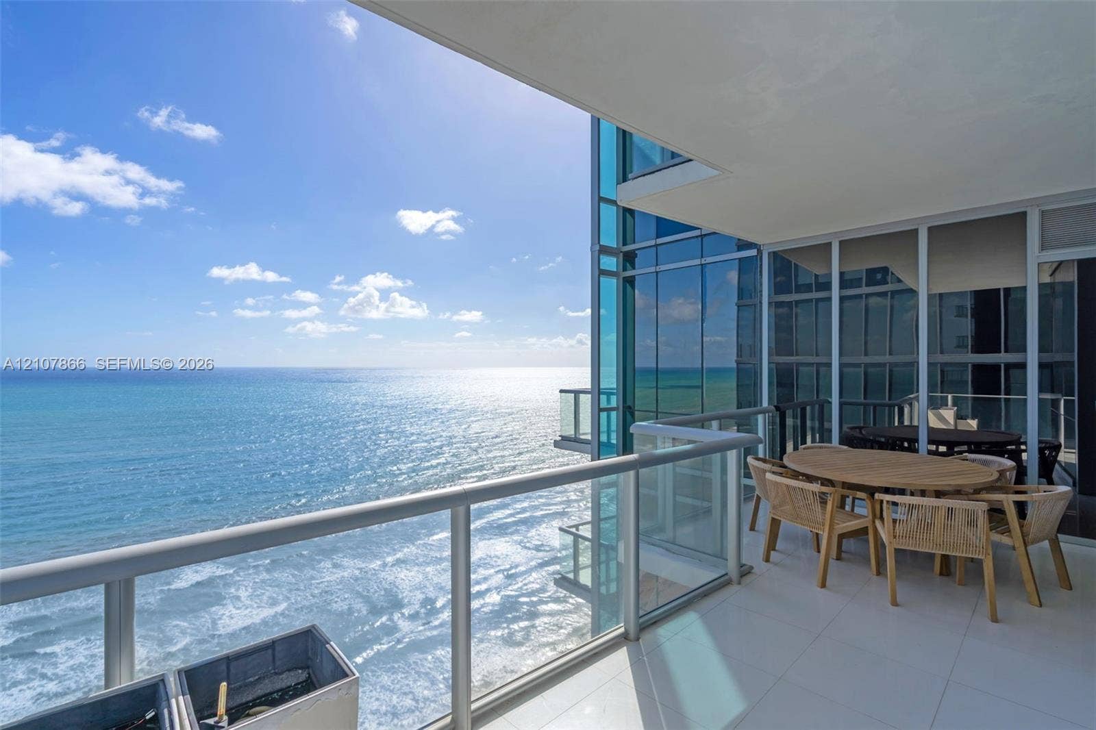 17121 Collins Avenue, #2608, Sunny Isles Beach, FL 33160 Covered balcony featuring white tile flooring, glass panel railings, and floor-to-ceiling glass wall panels overlooking the ocean