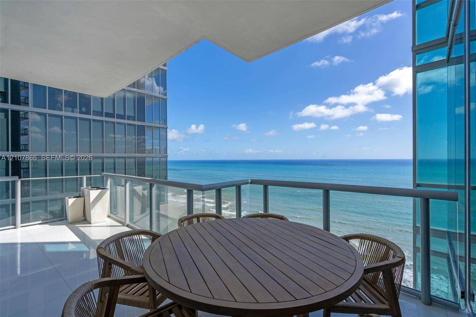 17121 Collins Avenue, #2608, Sunny Isles Beach, FL 33160 Covered balcony featuring glass paneled railings, white tile flooring, and ocean frontage