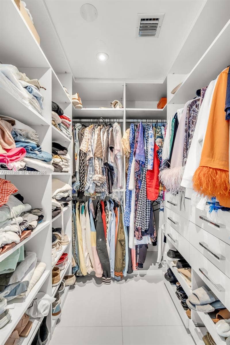 17121 Collins Avenue, #2608, Sunny Isles Beach, FL 33160 Custom walk-in closet featuring extensive white built-in cabinetry, tiered shelving, integrated hanging rods, recessed lighting, and large-format tile flooring