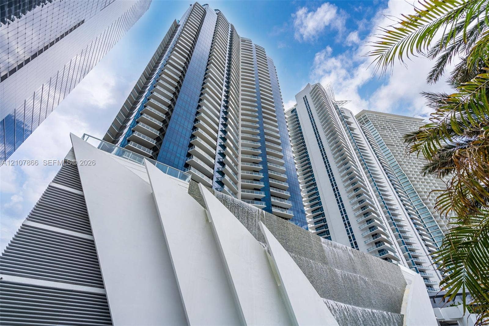 17121 Collins Avenue, #2608, Sunny Isles Beach, FL 33160 High-rise architectural exterior featuring glass curtain walls, private balconies with glass railings, and a tiered water feature
