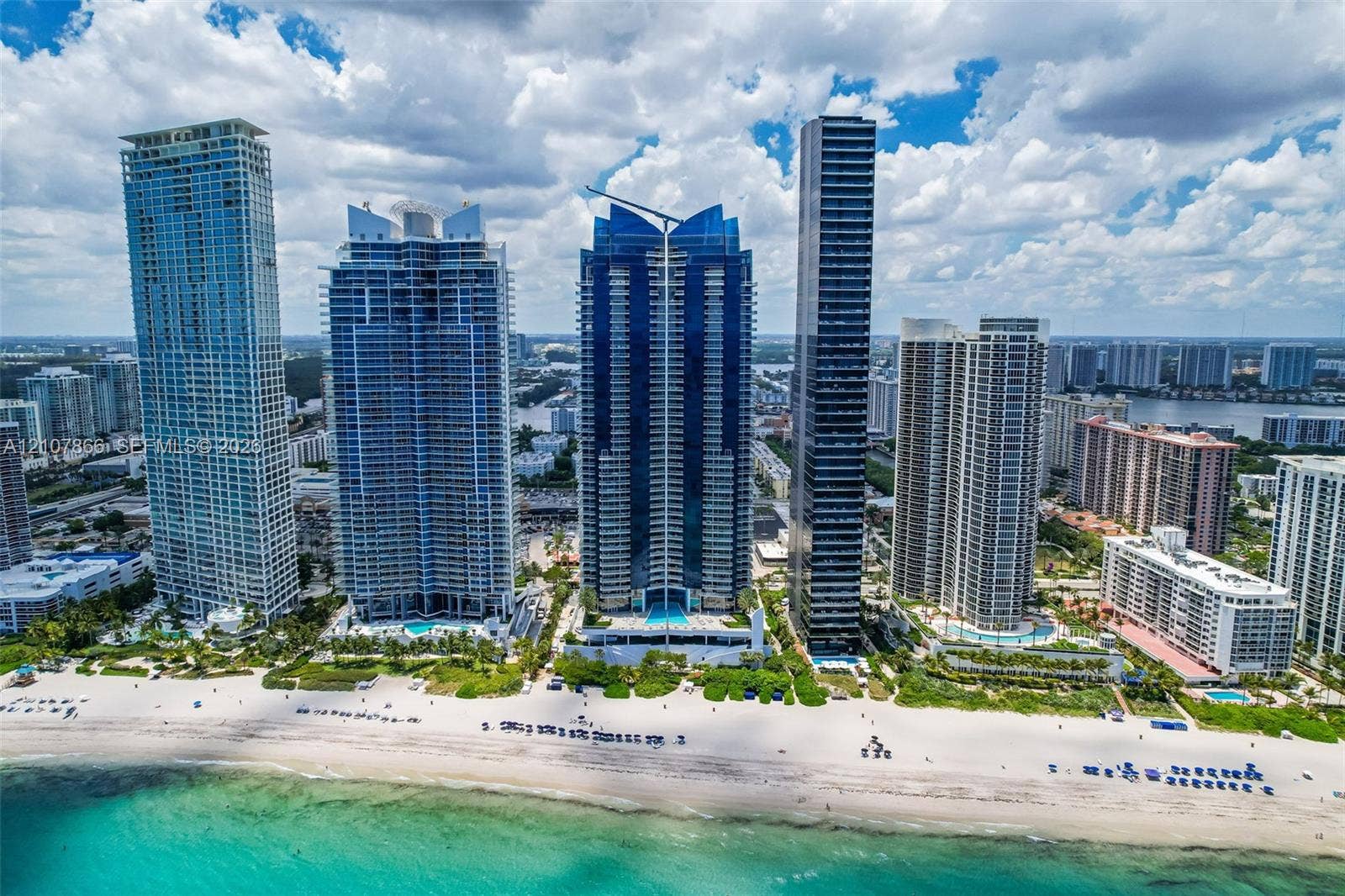 17121 Collins Avenue, #2608, Sunny Isles Beach, FL 33160 High-rise coastal development featuring glass-paneled architecture, direct oceanfront access, extensive white sand shoreline, and ground-level pool facilities