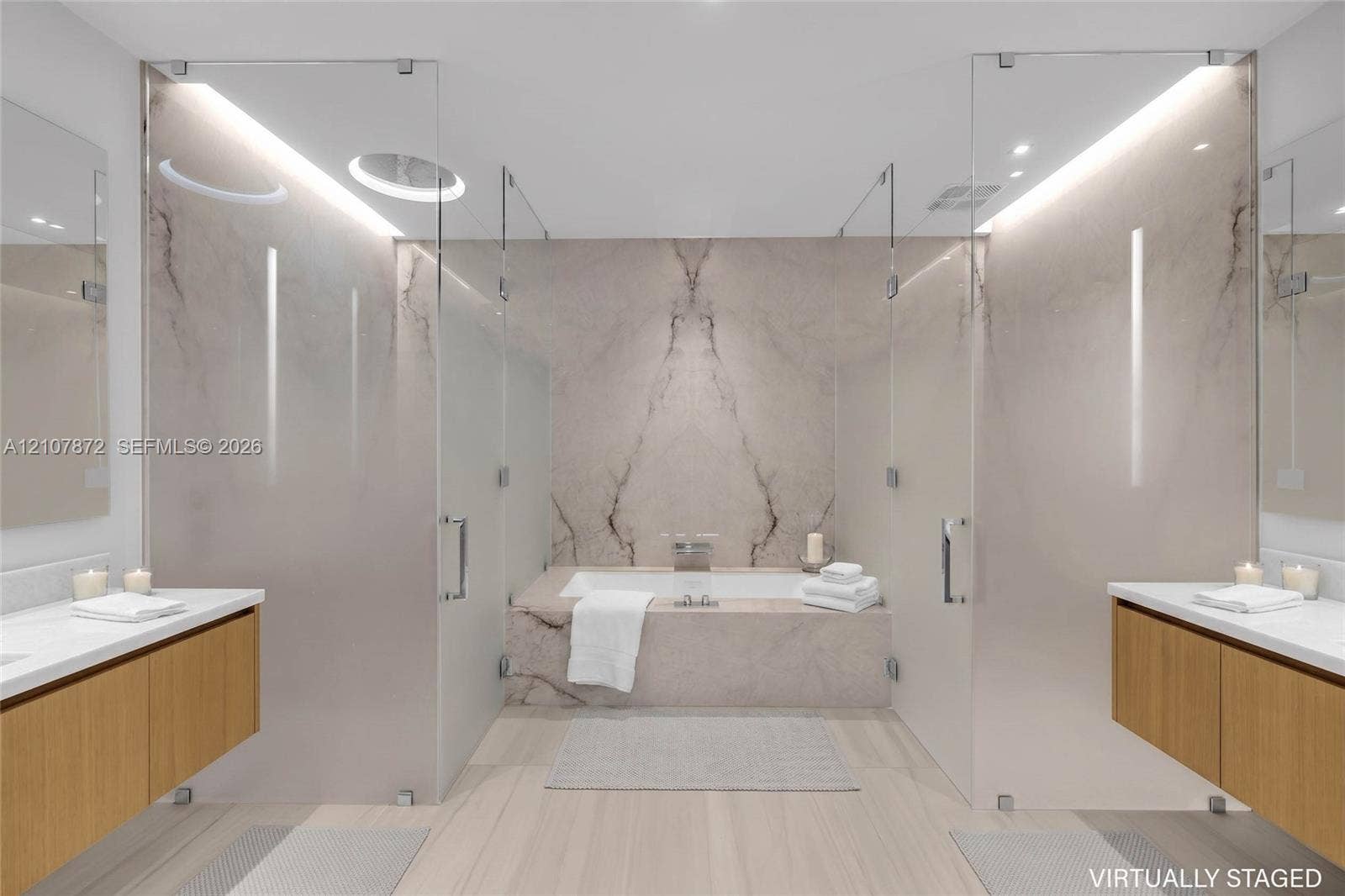 2221 SE 17th Street, #301, Fort Lauderdale, FL 33316 Dual floating wood-finish vanities with rectangular integrated sinks, stone-clad drop-in bathtub with wall-mounted faucet, full-height stone backsplash, and frameless glass-enclosed shower stalls with recessed overhead lighting