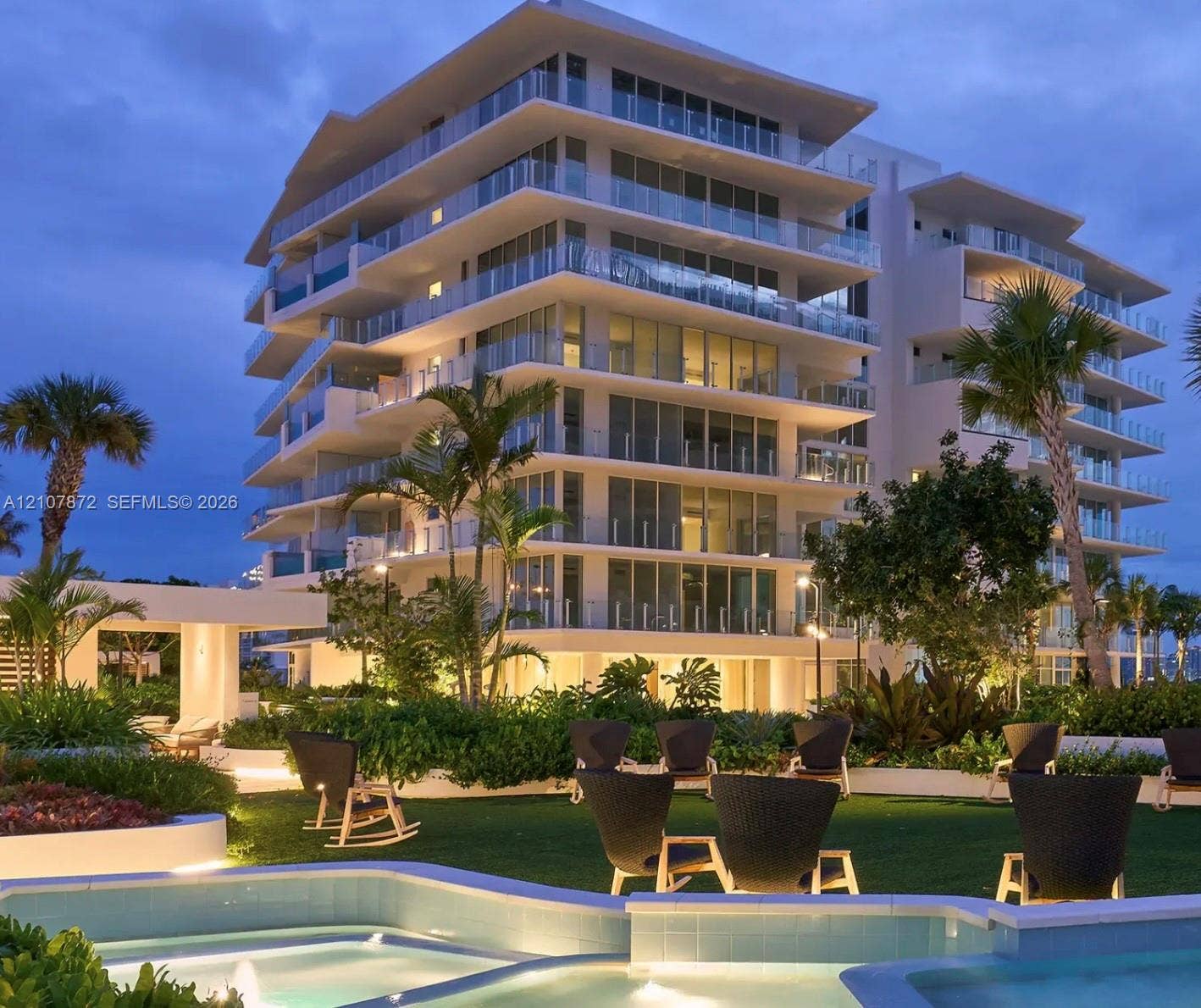 2221 SE 17th Street, #301, Fort Lauderdale, FL 33316 Mid-rise building exterior featuring tiered balconies with glass railings, an outdoor water feature with stone coping, and manicured landscaping