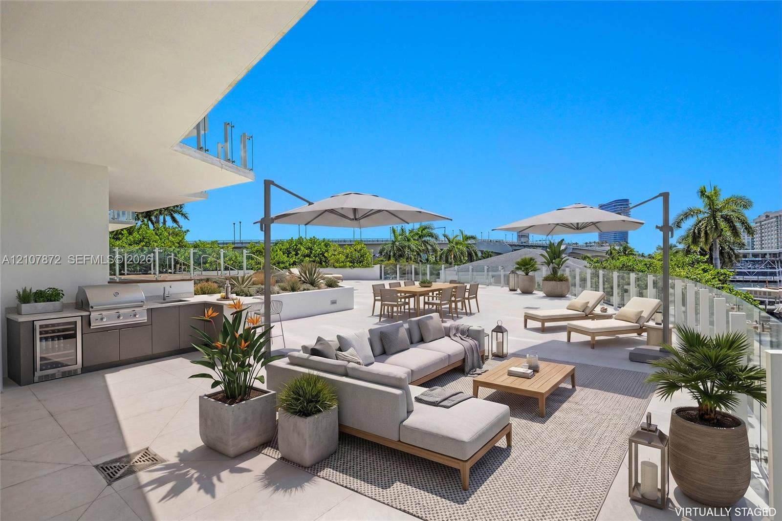 2221 SE 17th Street, #301, Fort Lauderdale, FL 33316 Expansive outdoor terrace featuring stone-tiled flooring, a built-in outdoor kitchen with stainless steel appliances, a bar refrigerator, and glass panel railing