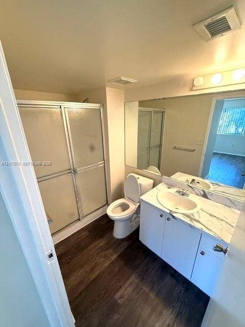 8402 Coral Lake Way, #8402, Coral Springs, Coral Springs, FL 33065 Bathroom featuring white cabinetry, stone-finish vanity countertop with an integrated oval basin, full-width wall mirror, wood-finish flooring, and a glass-enclosed shower