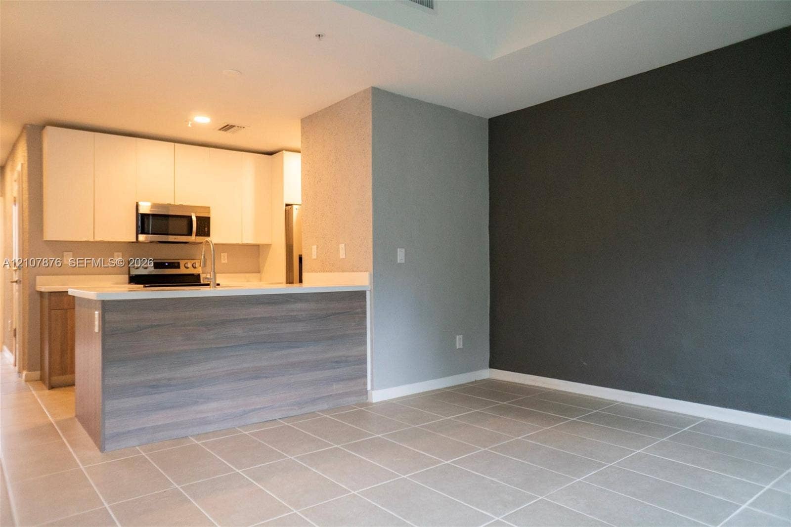 2526 Pierce Street, #8, Hollywood, Hollywood, FL 33020 Kitchen featuring white flat-panel cabinetry, light-toned stone-surface countertops, stainless steel appliances, a wood-finish peninsula, and large-format tile flooring