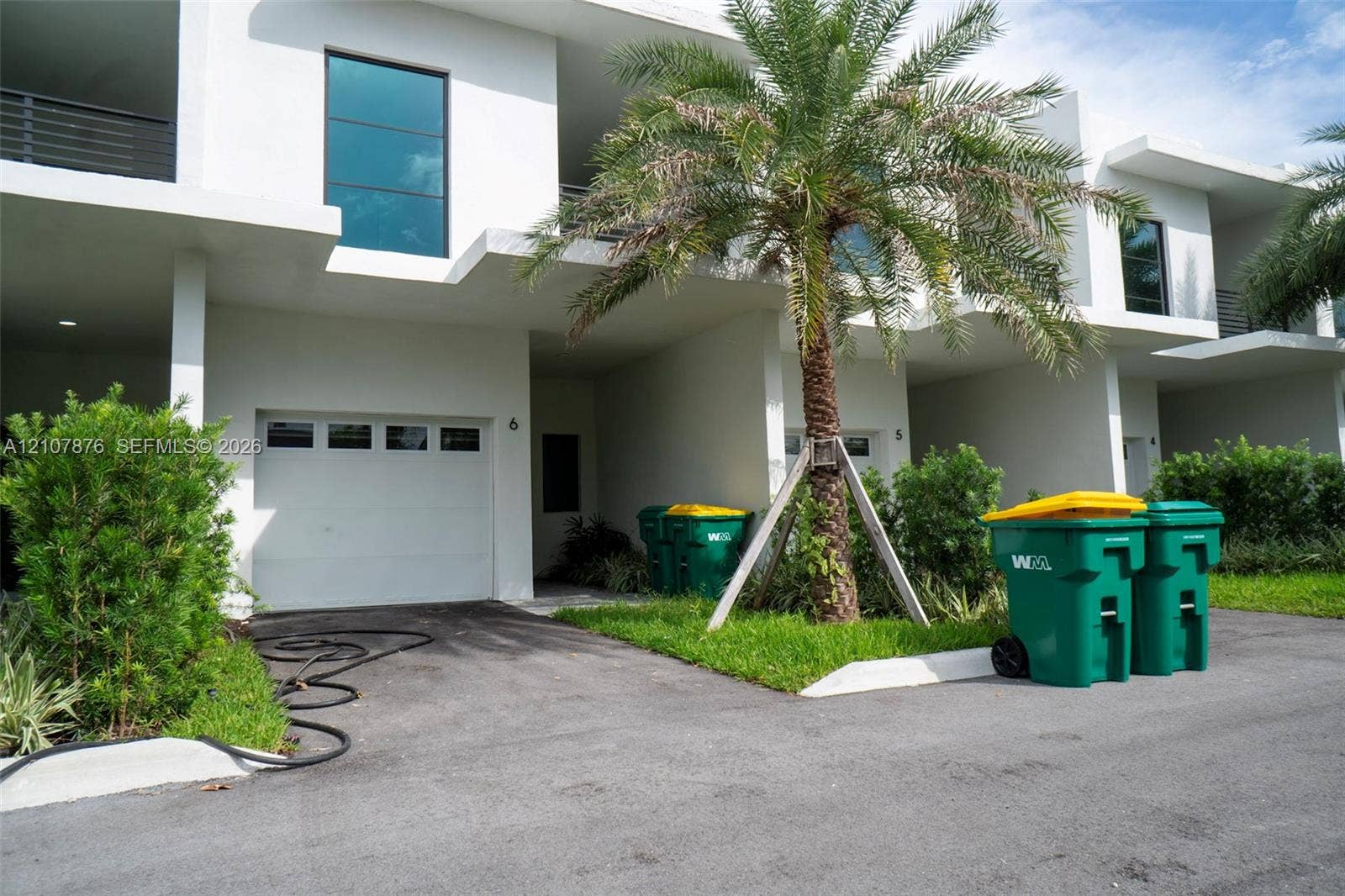 2526 Pierce Street, #8, Hollywood, Hollywood, FL 33020 Modern townhouse exterior featuring white stucco siding, integrated single-car garages, second-story balconies with glass railings, and mature palm landscaping