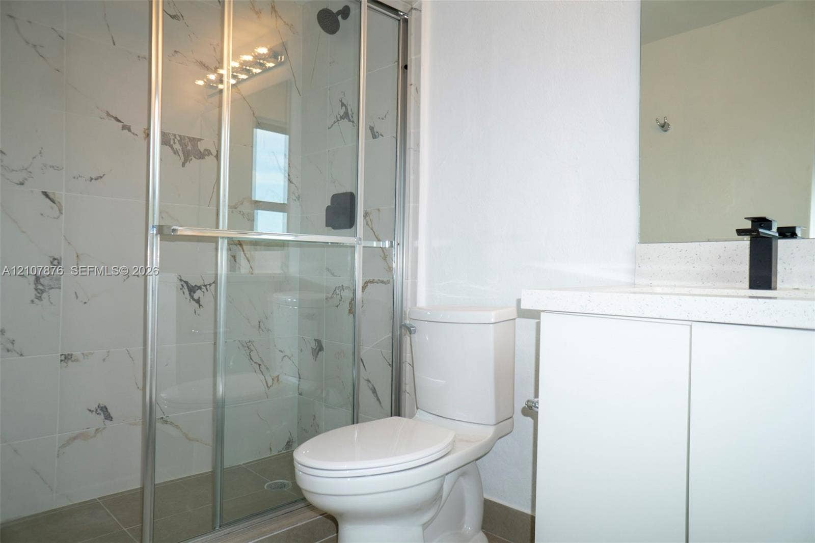 2526 Pierce Street, #8, Hollywood, Hollywood, FL 33020 Shower featuring a glass enclosure and patterned wall tile, complemented by a white vanity with a solid surface countertop and a matte black faucet