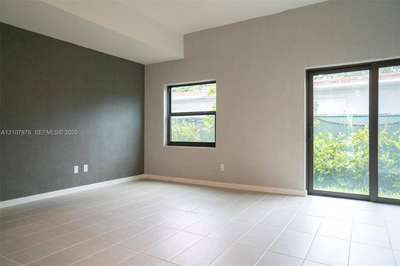 2526 Pierce Street, #8, Hollywood, Hollywood, FL 33020 Room featuring ceramic tile flooring, a charcoal-colored accent wall, neutral wall paint, a rectangular window, and a sliding glass door