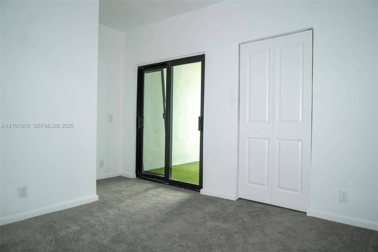 2526 Pierce Street, #8, Hollywood, Hollywood, FL 33020 Interior space featuring neutral carpeting, a two-panel sliding closet door, and a sliding glass door with a dark frame