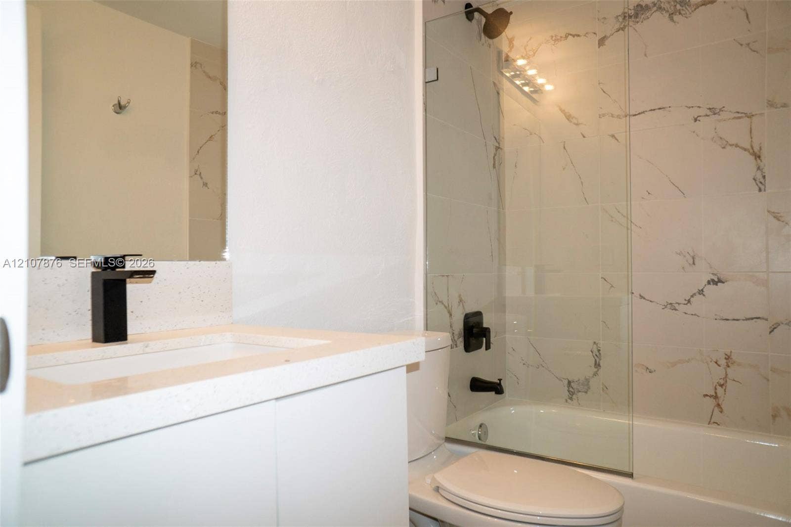 2526 Pierce Street, #8, Hollywood, Hollywood, FL 33020 Bathroom featuring a white vanity with a quartz countertop, matte black faucet, shower enclosure with floor-to-ceiling tile, and a glass shower panel
