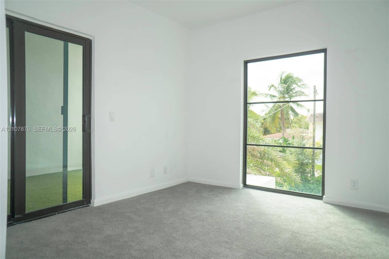 2526 Pierce Street, #8, Hollywood, Hollywood, FL 33020 Neutral-toned carpeting, full-height sliding glass door, and large rectangular window with dark-finish frames