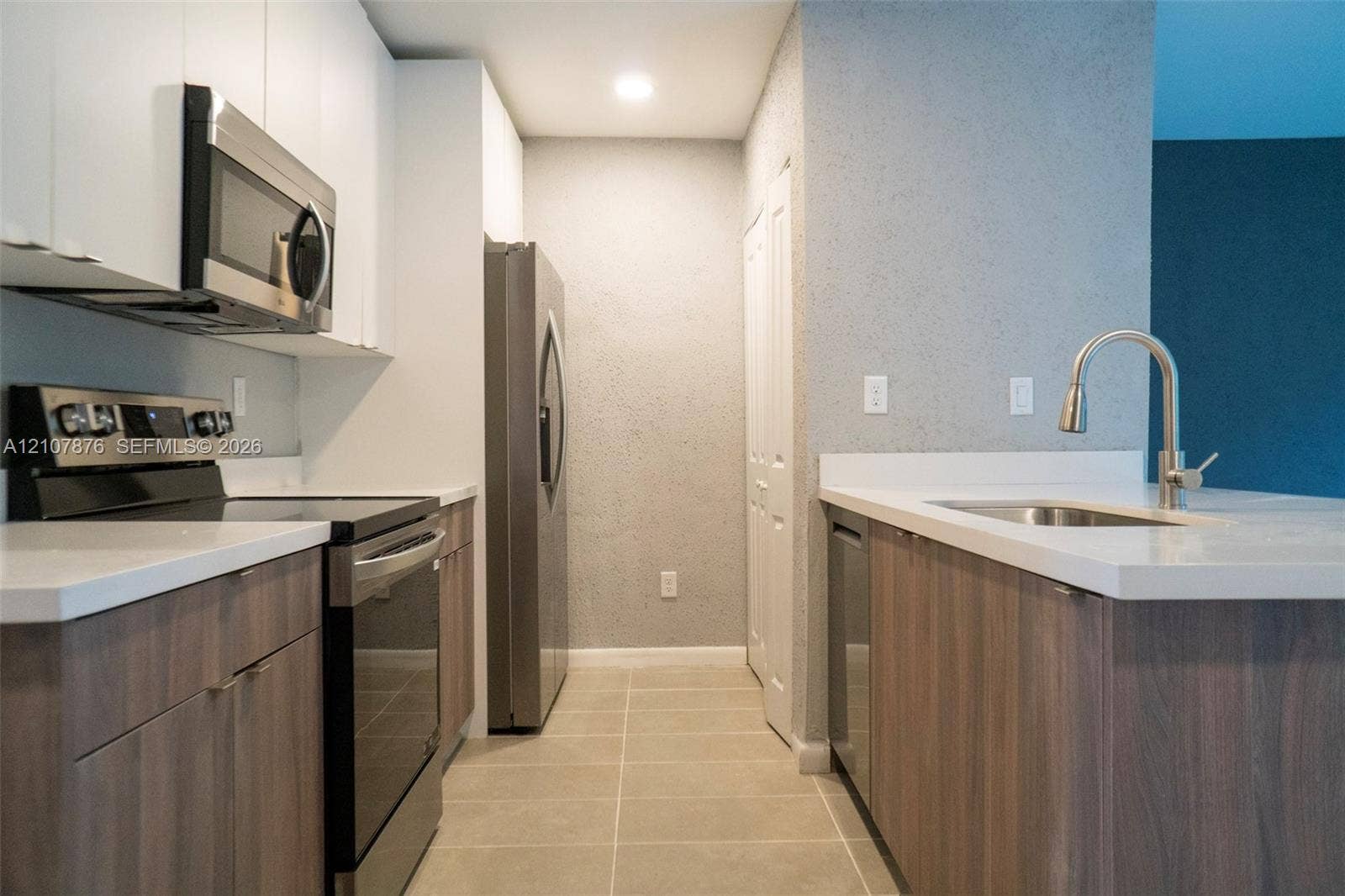 2526 Pierce Street, #8, Hollywood, Hollywood, FL 33020 Kitchen featuring two-tone cabinetry with white upper and wood-finish lower units, solid-surface countertops, stainless steel appliances, and tile flooring