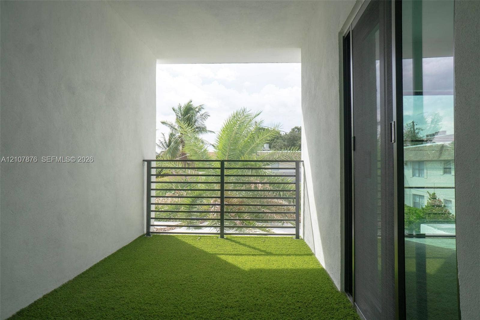 2526 Pierce Street, #8, Hollywood, Hollywood, FL 33020 Covered balcony featuring synthetic turf surfacing, horizontal metal railing, and a full-height glass sliding door
