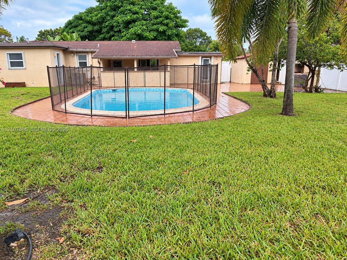 4840 NW 10th Terrace, Fort Lauderdale, Fort Lauderdale, FL 33309 Backyard featuring an in-ground swimming pool with removable mesh fencing, tiled pool deck, and mature palm trees