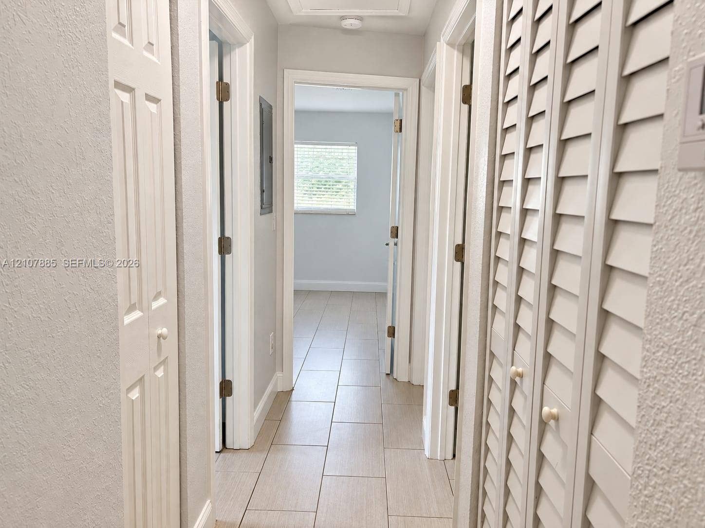 4840 NW 10th Terrace, Fort Lauderdale, Fort Lauderdale, FL 33309 Hallway featuring neutral-toned tile flooring, louvered closet doors, and multiple interior doorways