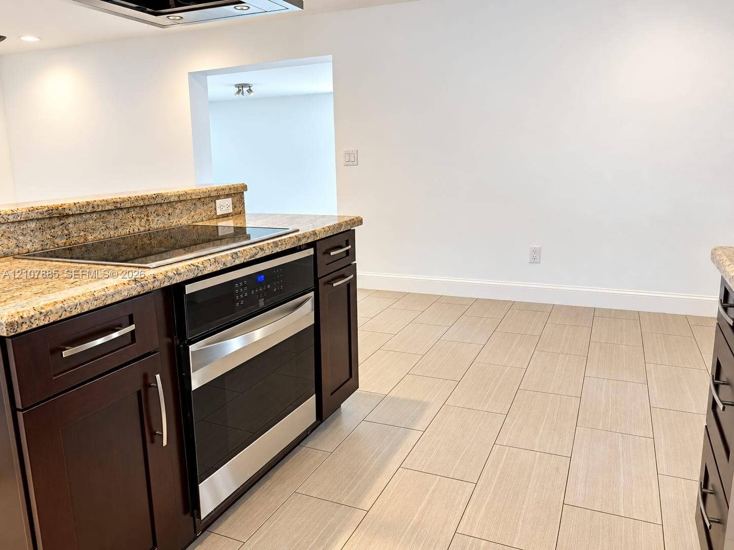 4840 NW 10th Terrace, Fort Lauderdale, Fort Lauderdale, FL 33309 Kitchen featuring dark cabinetry with metallic hardware, stone-finish countertops, an integrated glass cooktop, a stainless steel oven, and light-toned tile flooring