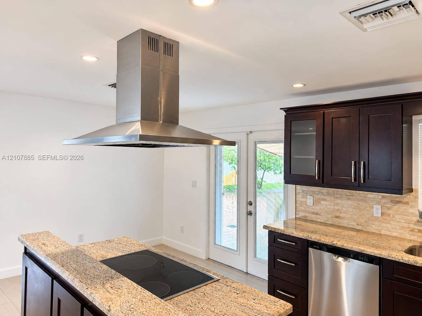 4840 NW 10th Terrace, Fort Lauderdale, Fort Lauderdale, FL 33309 Kitchen featuring dark wood cabinetry, stone countertops, stainless steel appliances, a center island with a built-in cooktop, and a stainless steel vent hood