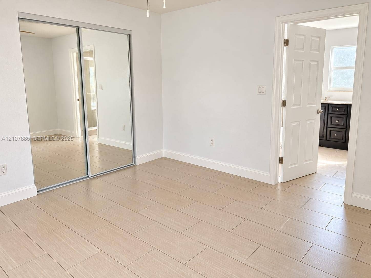 4840 NW 10th Terrace, Fort Lauderdale, Fort Lauderdale, FL 33309 Room interior featuring light-toned tile flooring, mirrored sliding closet doors, and a six-panel interior door