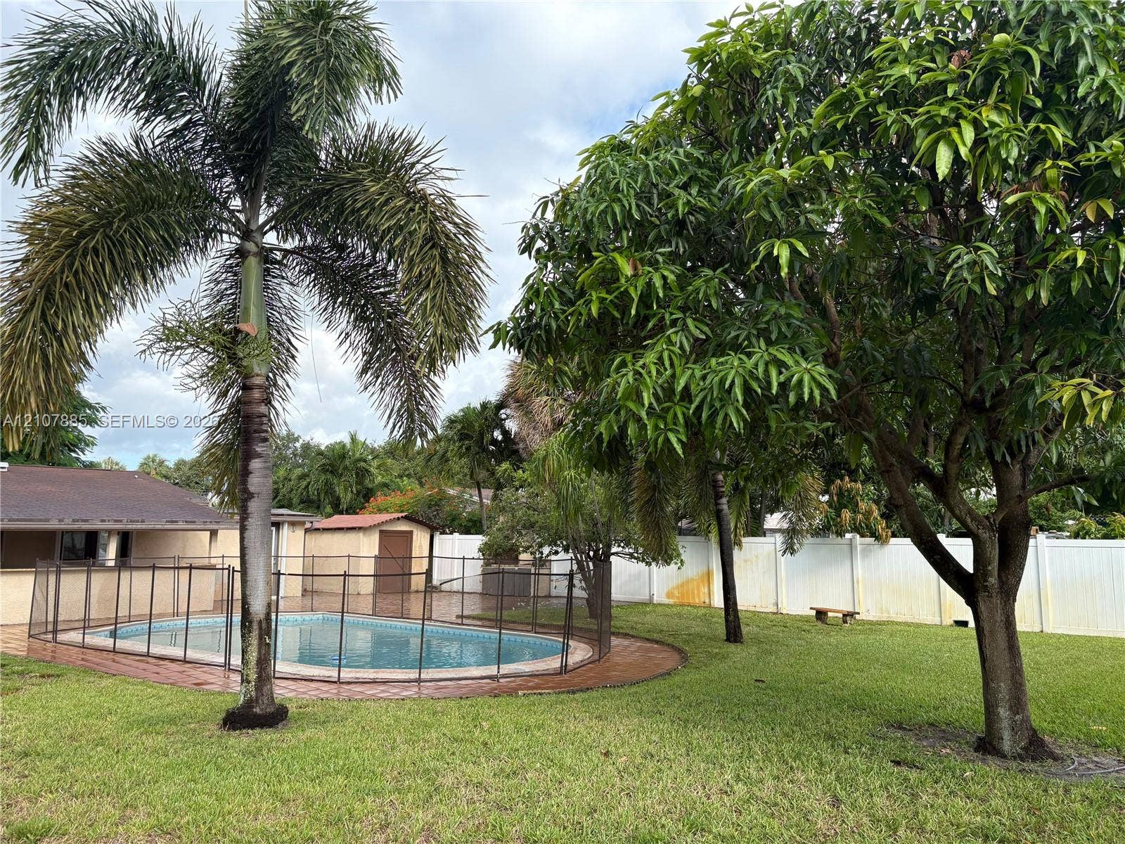 4840 NW 10th Terrace, Fort Lauderdale, Fort Lauderdale, FL 33309 Backyard featuring a swimming pool, safety fencing, mature landscaping, and a solid perimeter privacy fence
