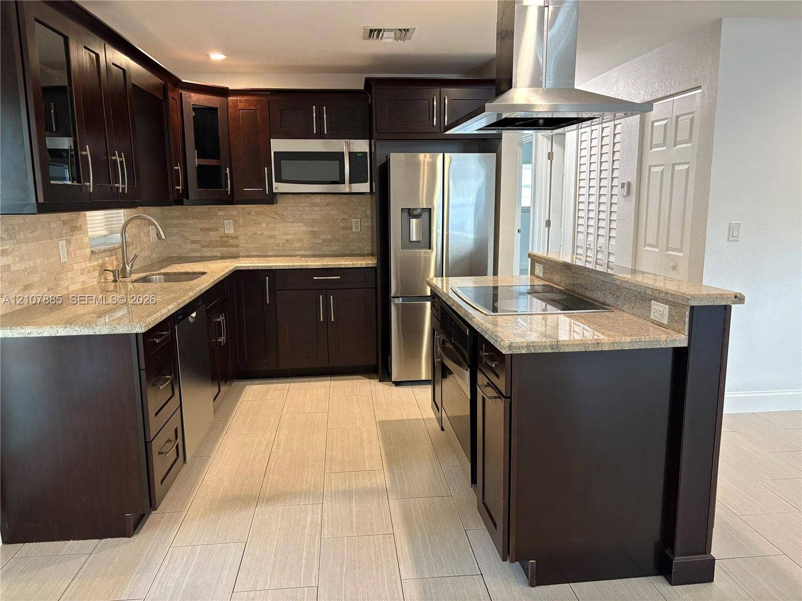4840 NW 10th Terrace, Fort Lauderdale, Fort Lauderdale, FL 33309 Kitchen featuring dark wood cabinetry, stone countertops, stacked-stone backsplash, stainless steel appliances, and a center island with a built-in cooktop