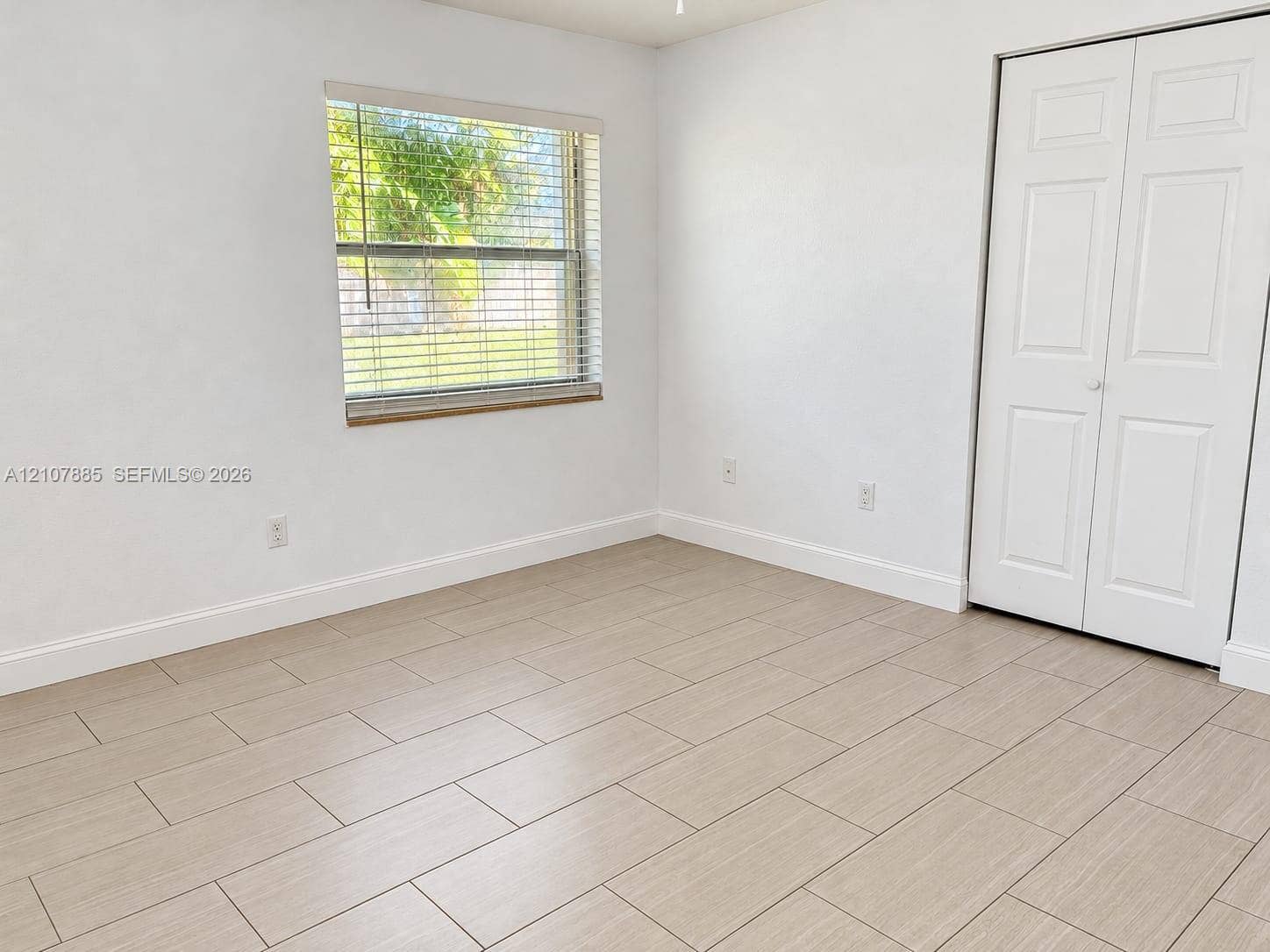 4840 NW 10th Terrace, Fort Lauderdale, Fort Lauderdale, FL 33309 Neutral-toned wood-finish tile flooring, white bi-fold closet doors, and horizontal window blinds