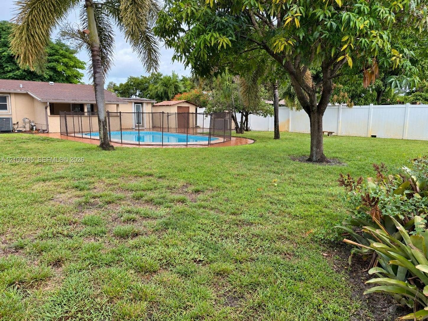 4840 NW 10th Terrace, Fort Lauderdale, Fort Lauderdale, FL 33309 Backyard featuring an in-ground swimming pool, perimeter safety fencing, mature trees, and a solid-panel privacy fence