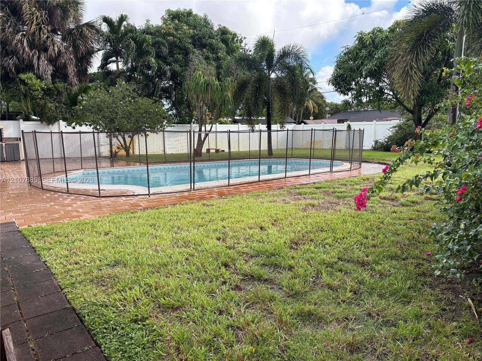 4840 NW 10th Terrace, Fort Lauderdale, Fort Lauderdale, FL 33309 Backyard featuring an in-ground swimming pool, mesh safety fencing, paver patio, lawn, and perimeter privacy fencing