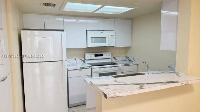 8411 Coral Lake Manor, #8441, Coral Springs, Coral Springs, FL 33065 Kitchen featuring high-gloss white cabinetry, stone-patterned countertops, a stainless steel sink with a goose-neck faucet, and white appliances including a built-in microwave and range