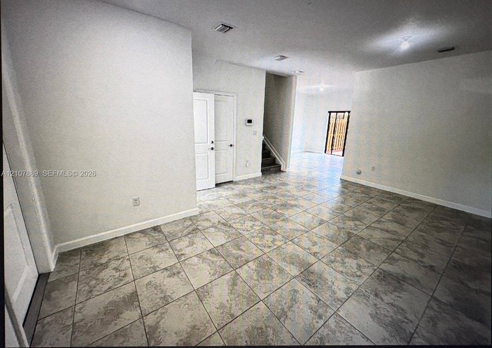 Interior space featuring large-format stone-patterned tile flooring, neutral wall finish, recessed lighting, and interior paneled doors