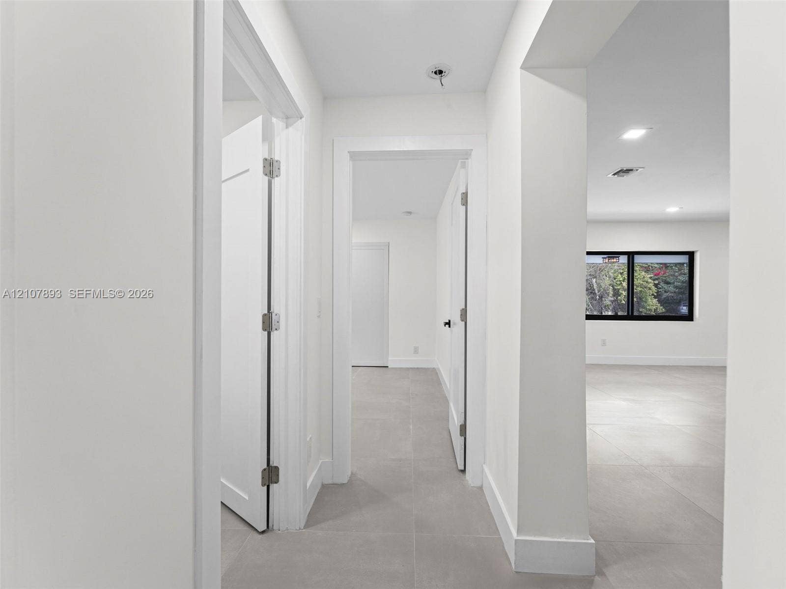 610 NE 164th Terrace, Miami, FL 33162 Neutral-toned large-format tile flooring, crisp white walls, recessed ceiling lighting, and black-trimmed window frames