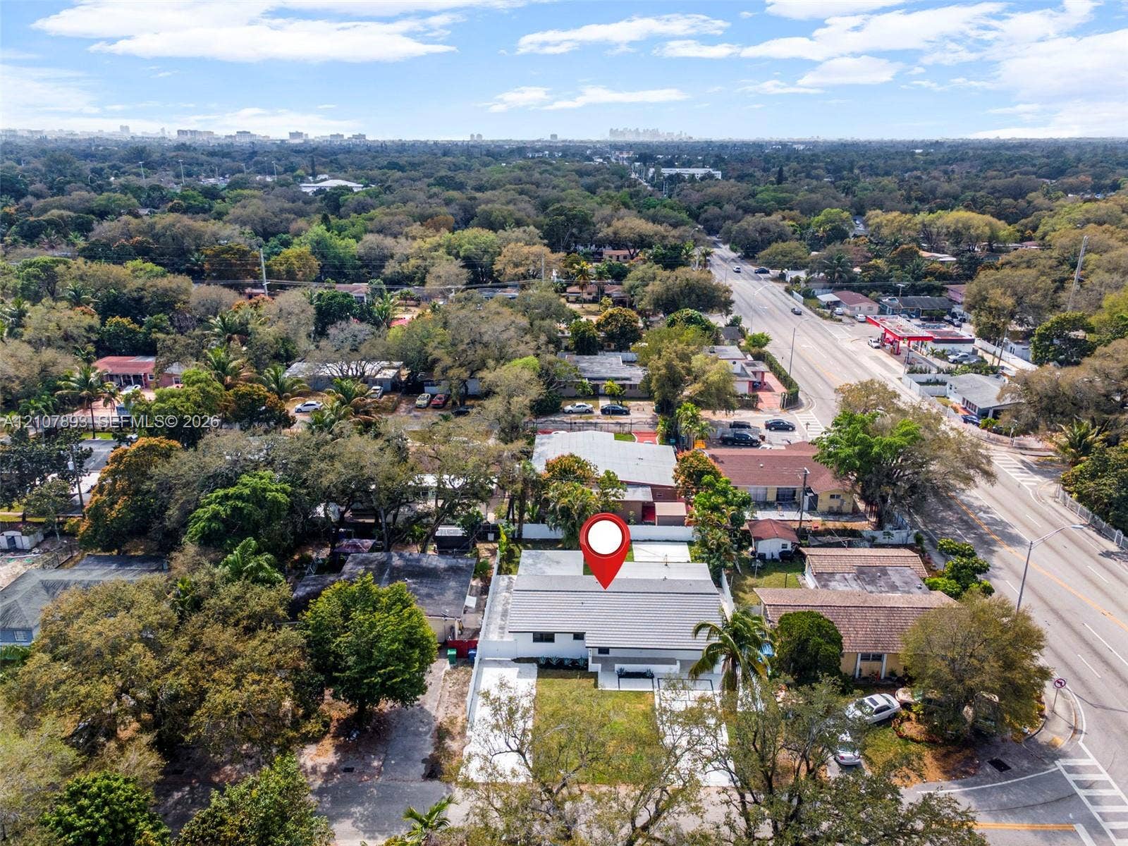 610 NE 164th Terrace, Miami, FL 33162 Aerial perspective featuring a single-story residence with a light-toned exterior, gabled roof, paved driveway, and perimeter fencing