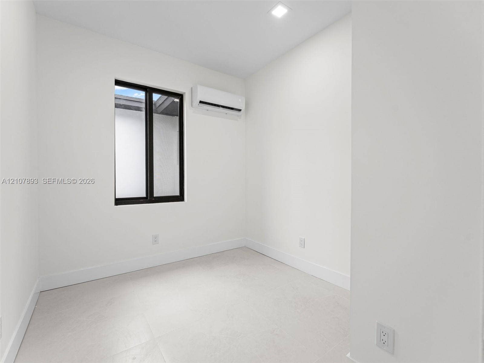 610 NE 164th Terrace, Miami, FL 33162 Neutral room featuring light-toned tile flooring, recessed ceiling lighting, a wall-mounted ductless air conditioning unit, and a window with a dark frame