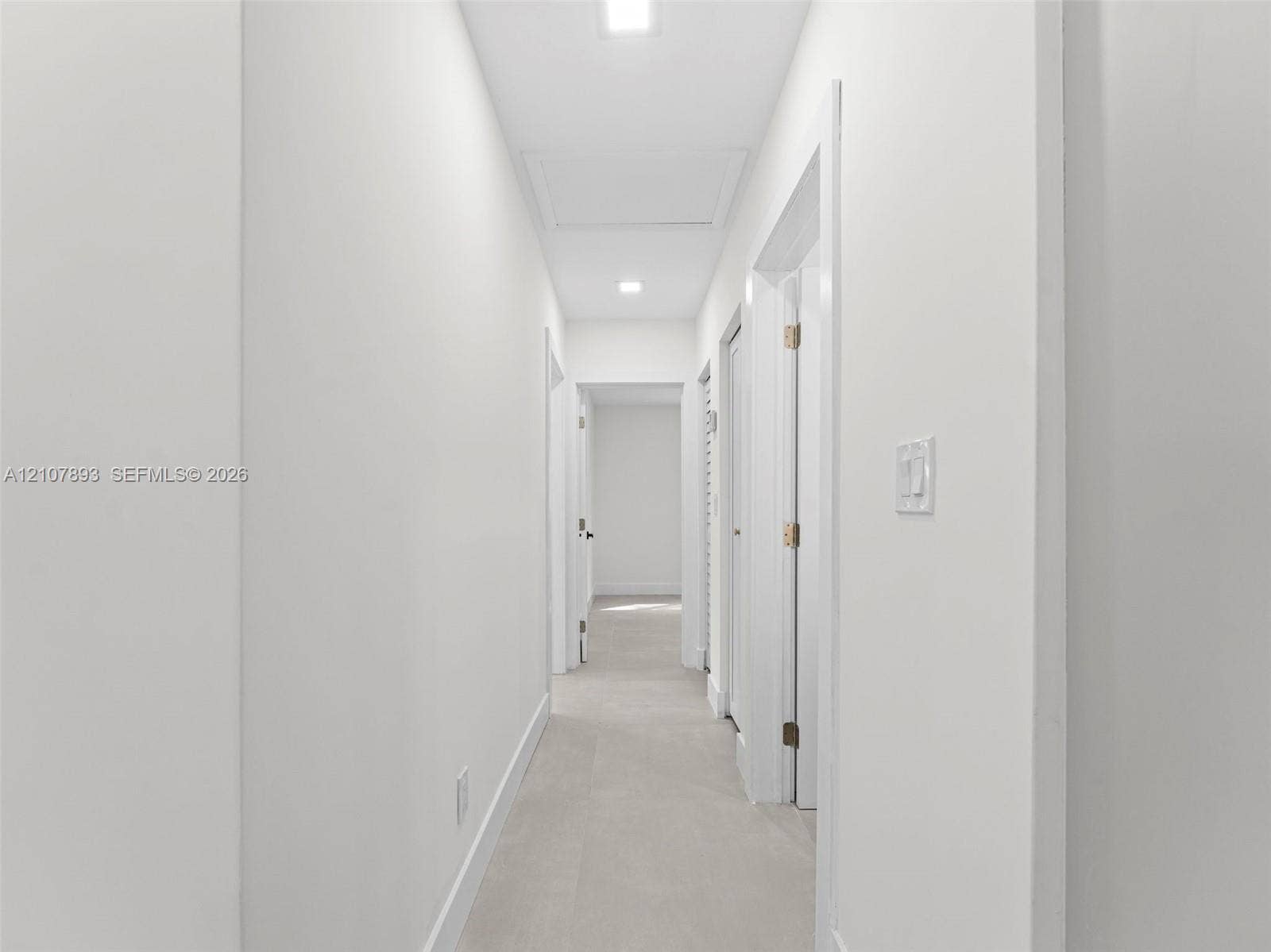 610 NE 164th Terrace, Miami, FL 33162 Hallway featuring neutral-toned tile flooring, recessed ceiling lighting, and crisp white wall finishes