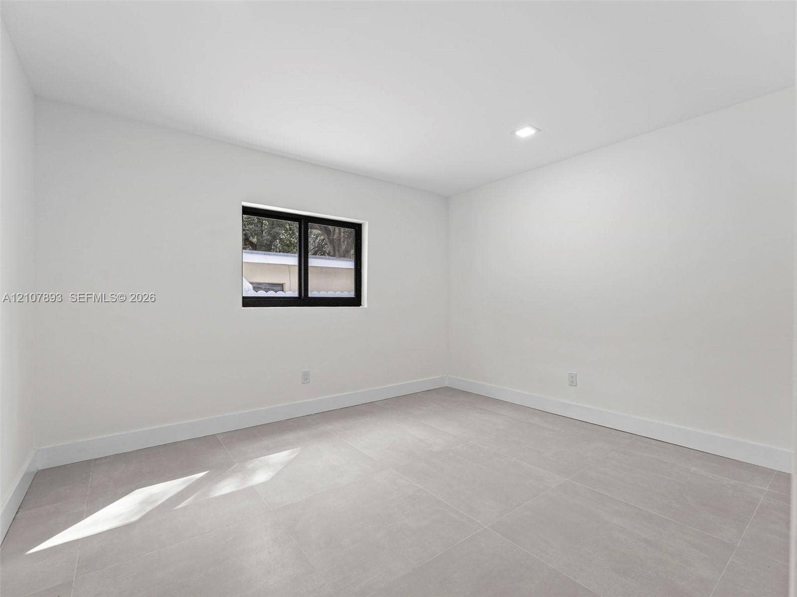 610 NE 164th Terrace, Miami, FL 33162 Neutral-toned tile flooring, recessed ceiling lighting, and a single-pane window with a black frame
