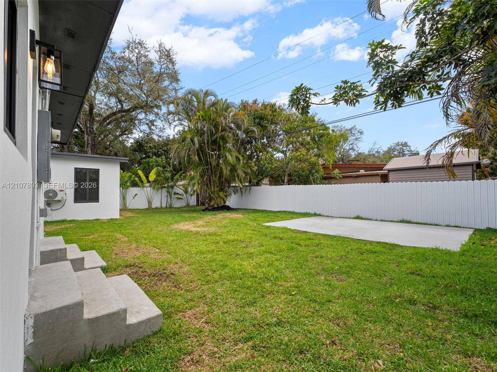 610 NE 164th Terrace, Miami, FL 33162 Fenced backyard featuring a manicured lawn, concrete patio, concrete stairs, and mature landscaping