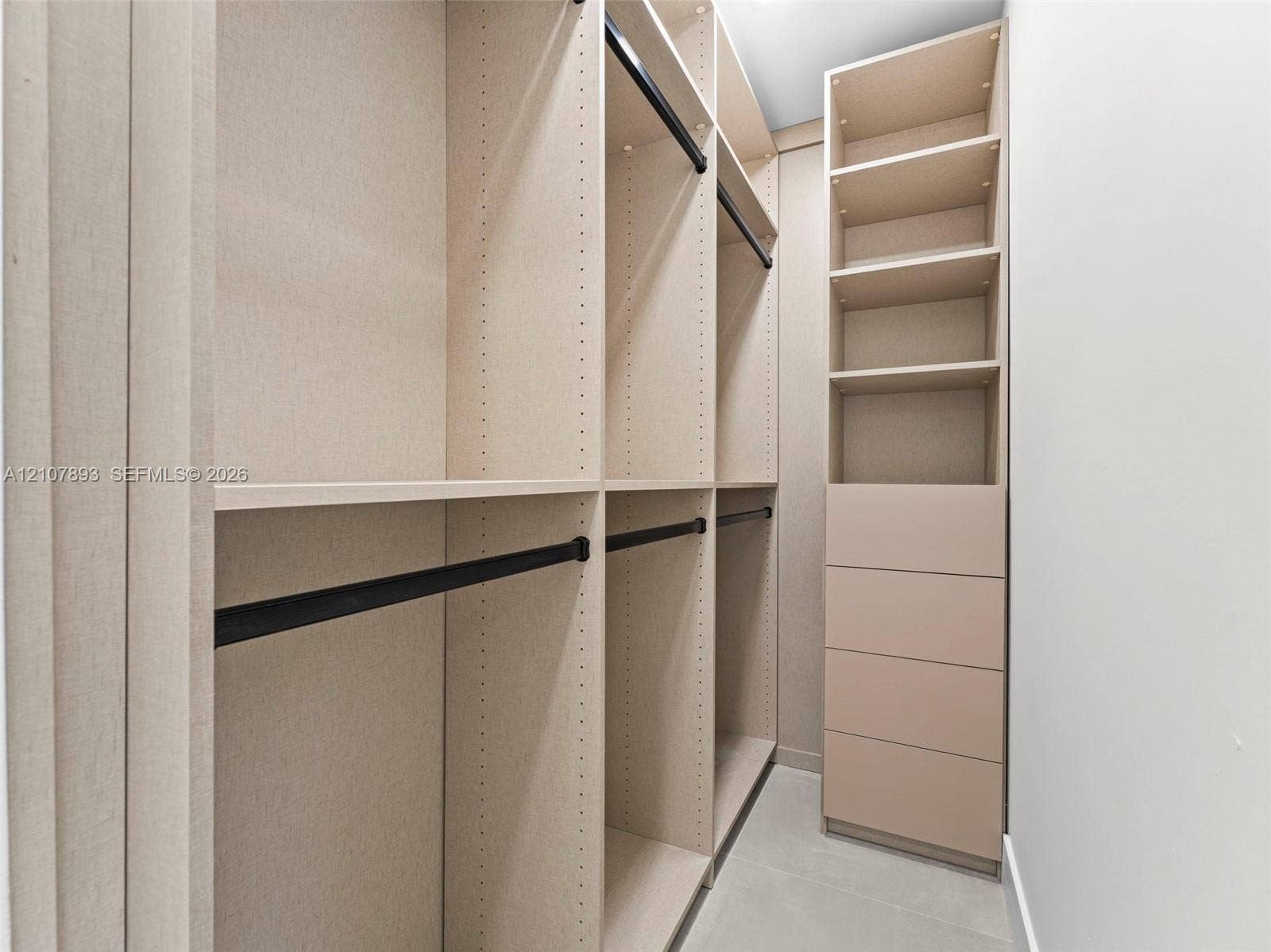 610 NE 164th Terrace, Miami, FL 33162 Custom reach-in closet featuring floor-to-ceiling shelving, integrated drawer stack, multiple hanging rods with matte black finish, and textured light-toned cabinetry