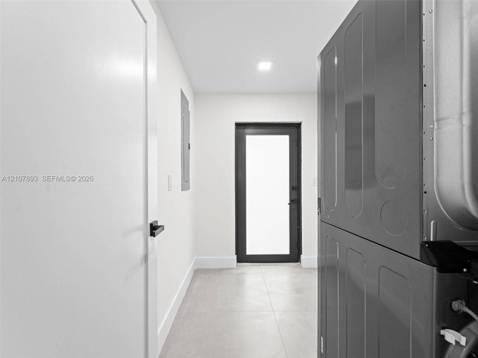 610 NE 164th Terrace, Miami, FL 33162 Neutral-toned tiled flooring, modern glass-panel exterior door, and matte black hardware