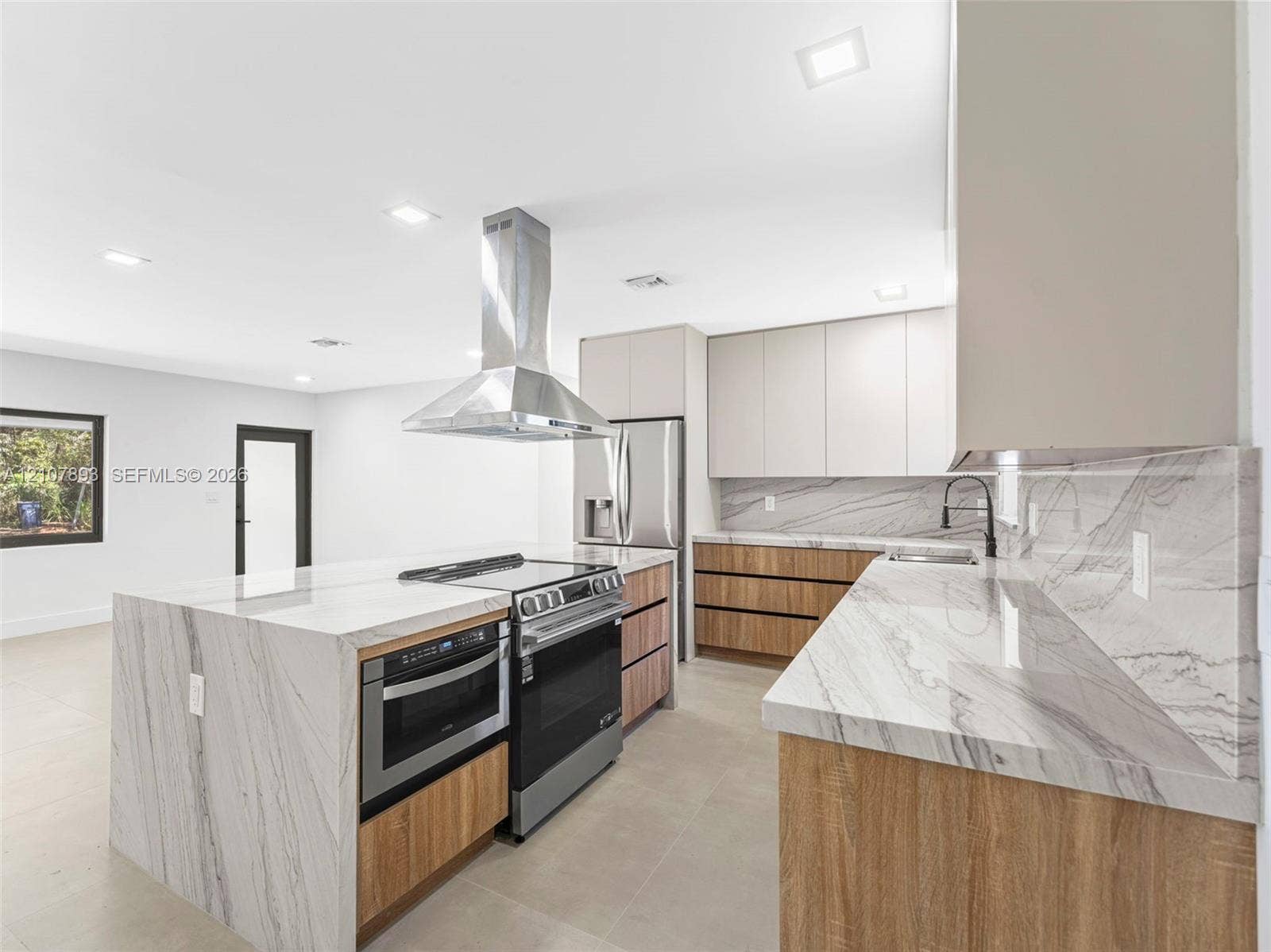 610 NE 164th Terrace, Miami, FL 33162 Kitchen featuring waterfall-edge stone countertops, wood-finish cabinetry, stainless steel range and built-in microwave, stainless steel chimney-style range hood, and tile flooring