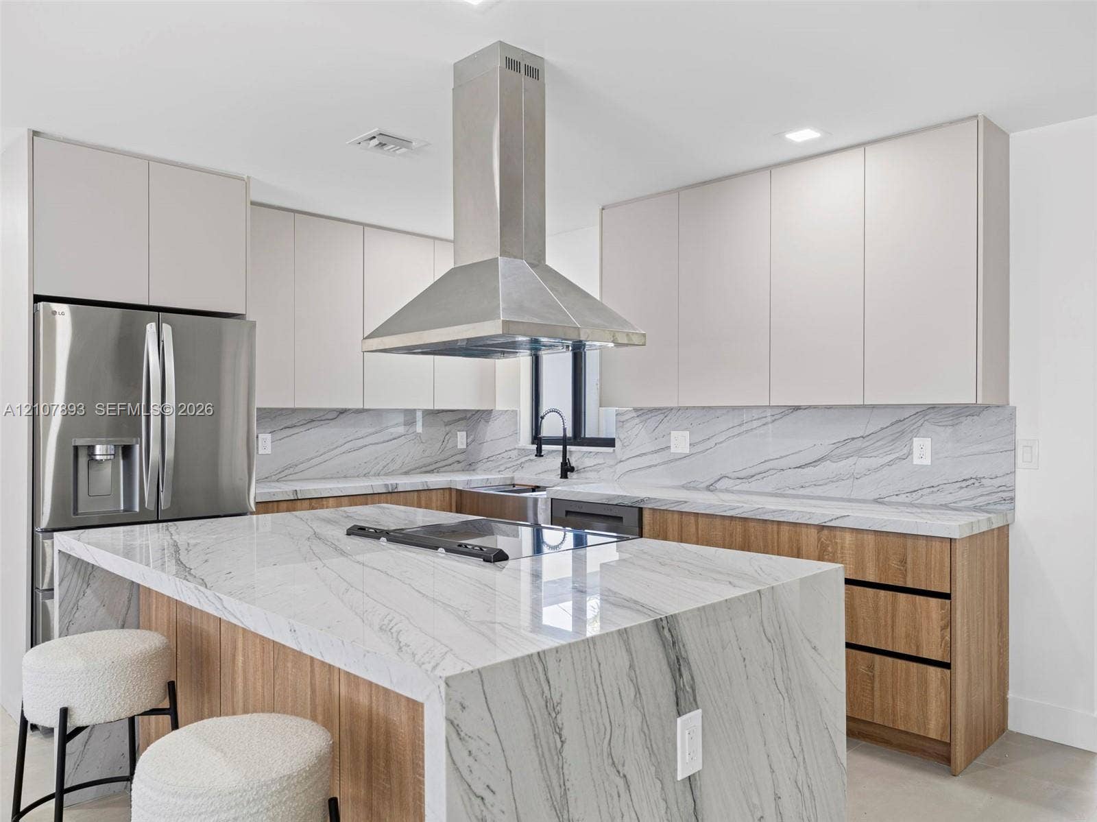 610 NE 164th Terrace, Miami, FL 33162 Kitchen featuring waterfall-edge stone countertops, stainless steel chimney-style range hood, dual-tone cabinetry, and wood-finish lower cabinetry