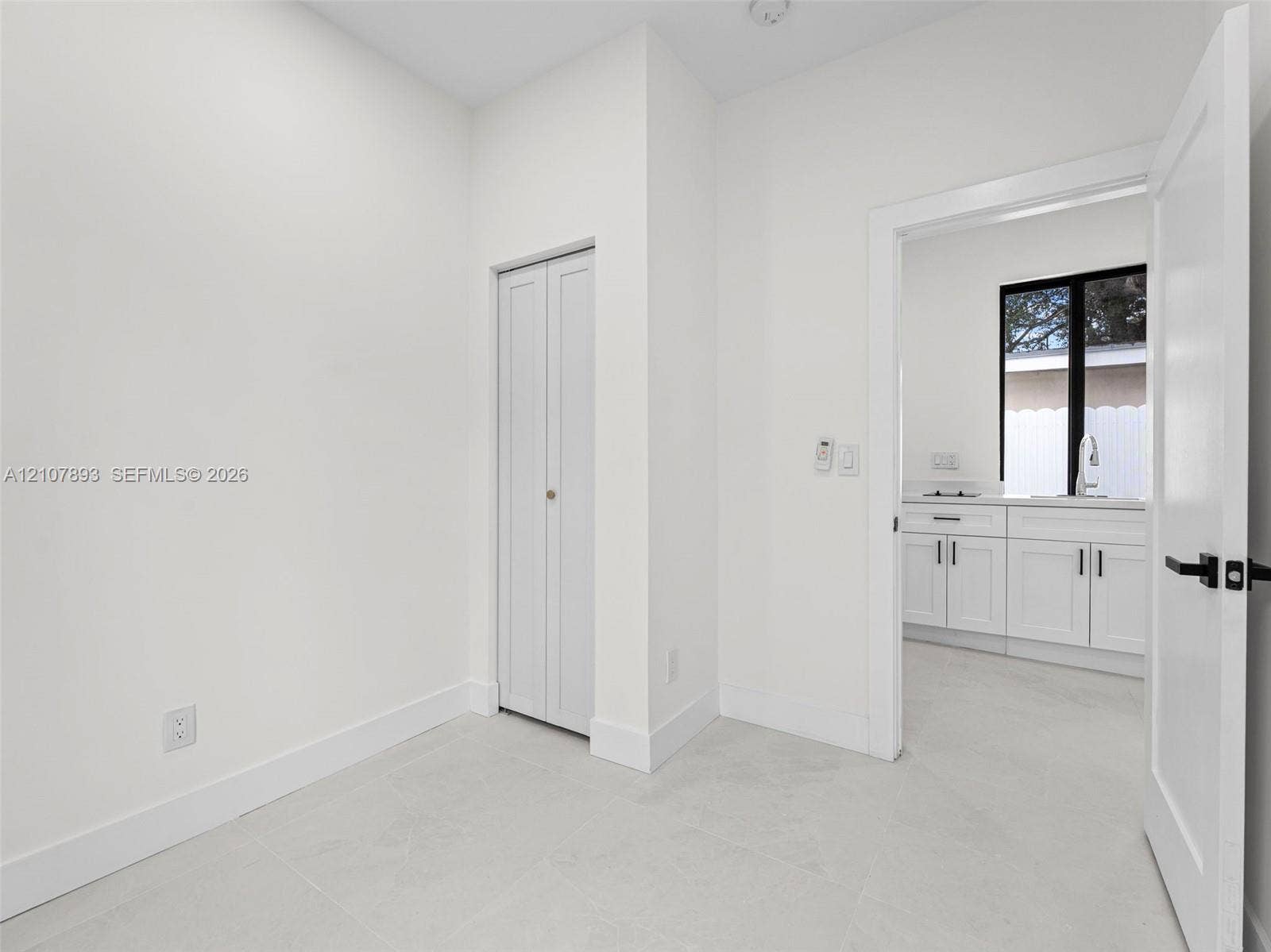 610 NE 164th Terrace, Miami, FL 33162 Neutral-toned tile flooring, bi-fold closet doors, and interior doors featuring matte black hardware