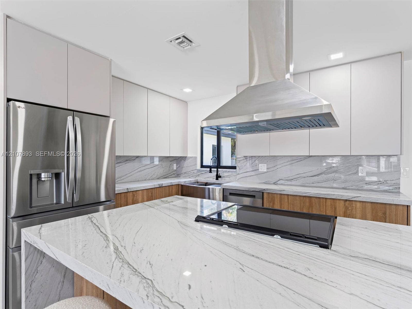 610 NE 164th Terrace, Miami, FL 33162 Kitchen featuring floor-to-ceiling flat-panel cabinetry, a central island with a stone countertop, a full-height stone backsplash, stainless steel appliances, and a stainless steel chimney-style range hood