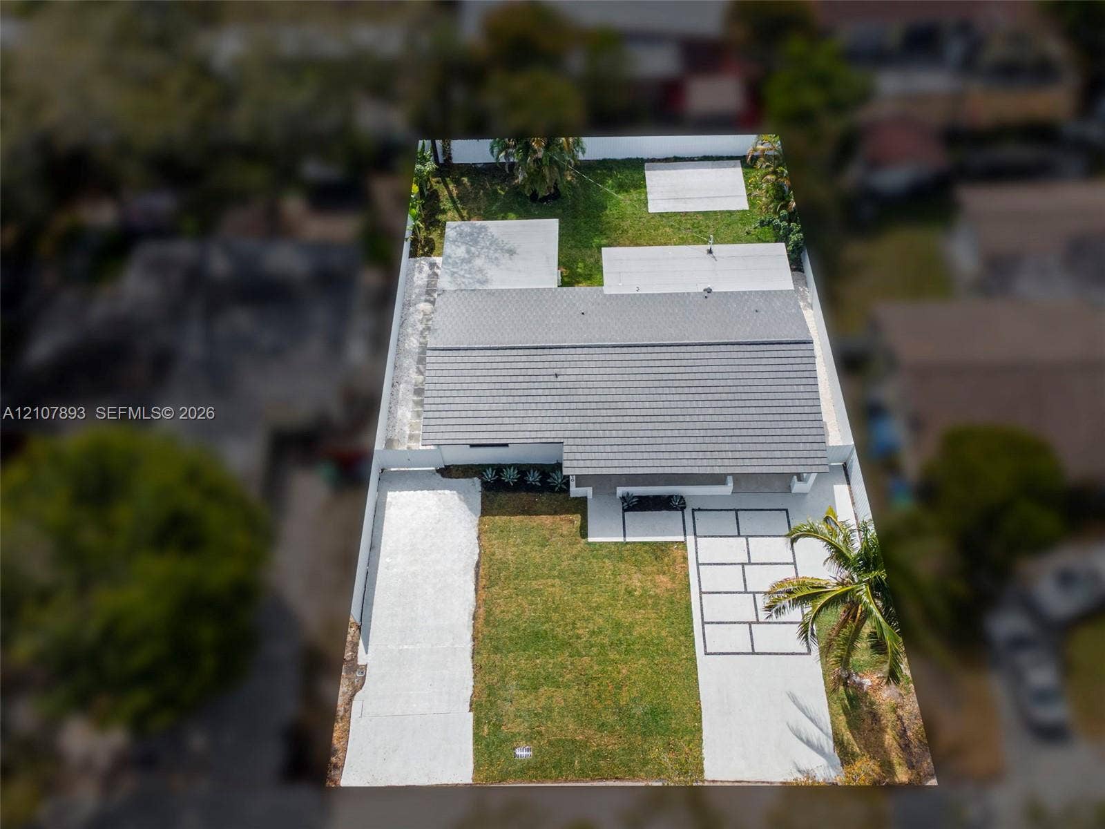 610 NE 164th Terrace, Miami, FL 33162 Aerial view of property featuring a concrete tile roof, paver driveway, concrete parking pad, manicured lawn, and perimeter privacy fencing