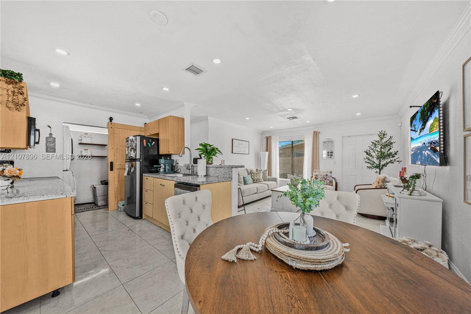 Kitchen featuring light wood-finish cabinetry, stone-style countertops, recessed lighting, tile flooring, and a sliding barn-style door
