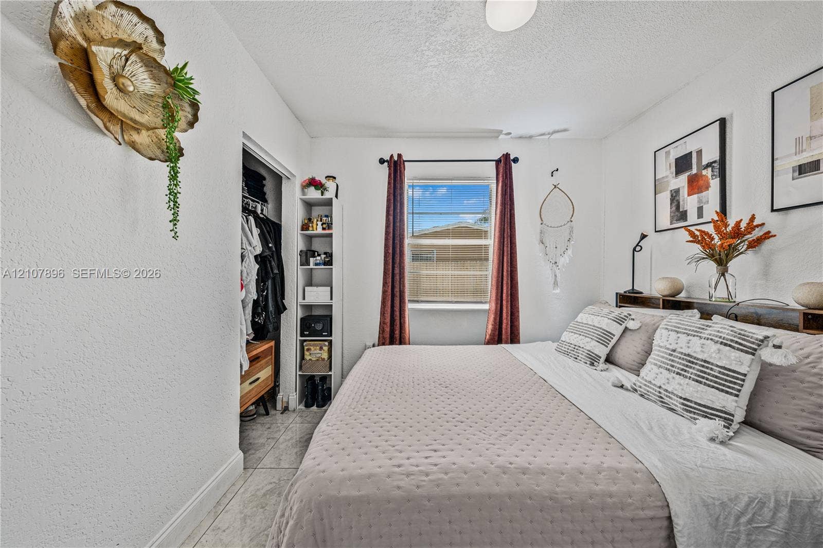 Bedroom featuring neutral wall paint, tiled flooring, and a window with a rod-mounted curtain set