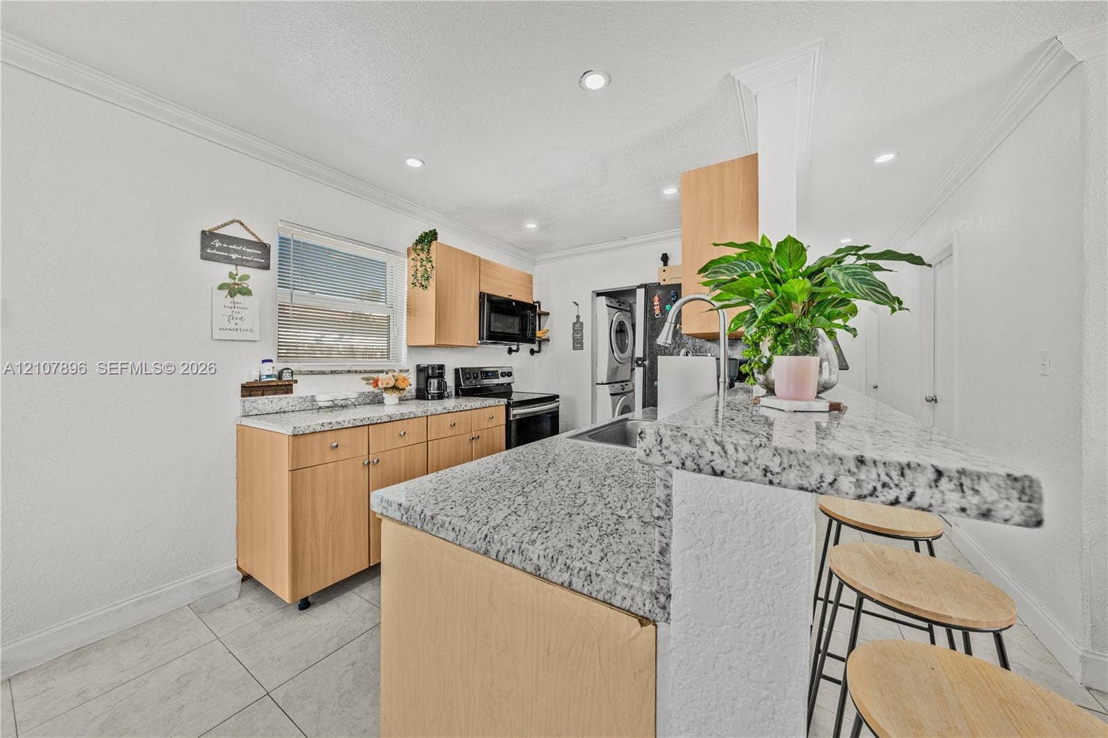 Kitchen featuring natural wood-finish cabinetry, stone-style countertops, recessed ceiling lighting, tile flooring, and a breakfast bar